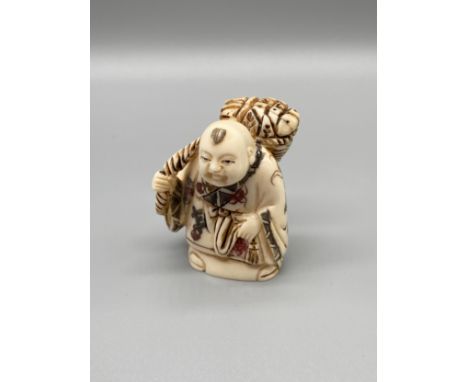 An early 20th century Japanese hand carved bone netsuke of a gentleman carrying a basket on his back. Signed. [5.3cm in heigh