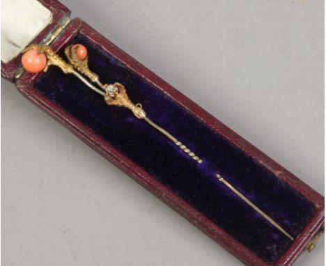 Three Victorian stick pins in a case. Claw set, two with coral and one with a diamond.