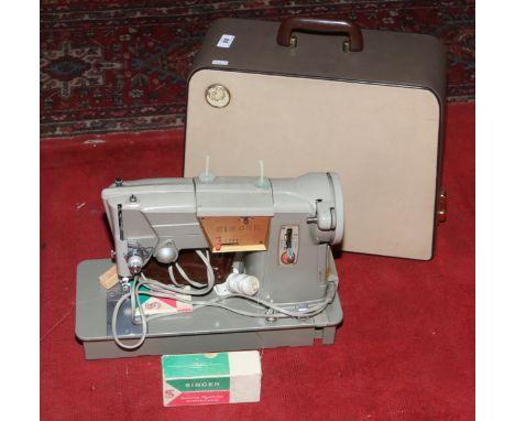 A cased electric Singer sewing machine with manual and attachments.