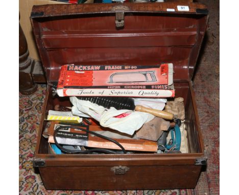 Old tin travelling trunk containing assorted hand tools.