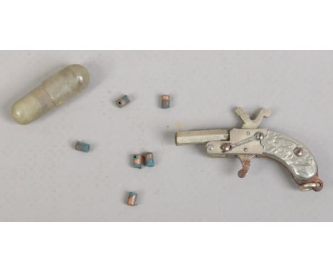 A novelty miniature watch chain fob formed as a firing gun and with accoutrements.