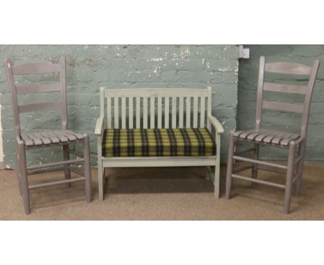 A pair of grey painted ladder back kitchen chairs.