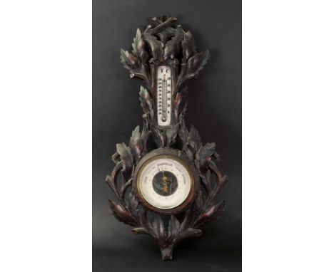A Black Forest combined barometer and thermometer, circa 1900, the lindenwood case carved and pierced with leaves and branche