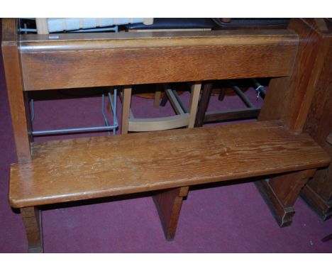 An early 20th century pitched pine two seater church pew, having an integral rear shelf raised on stepped end supports, width