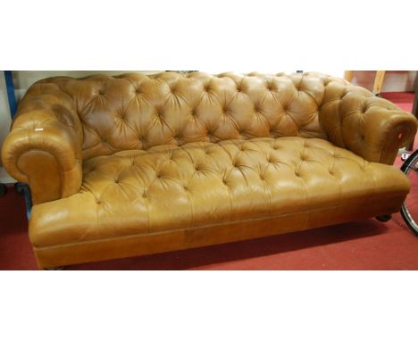 A good quality contemporary tan leather and button back upholstered three-seater Chesterfield, raised on walnut turned bun su