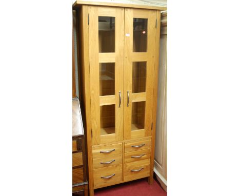 A contemporary joined light oak double door display cabinet having six short lower drawers, width 79.5cm