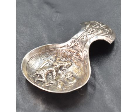 A George V silver caddy spoon, the bowl with embossed interior scene, the handle with foliate scrolls, marked 925 along side 