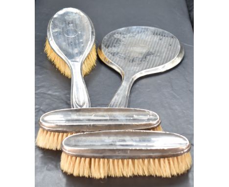 A George V silver mounted four-piece brush set, comprising hand mirror, hair brush and two clothes brushes, each with bands o