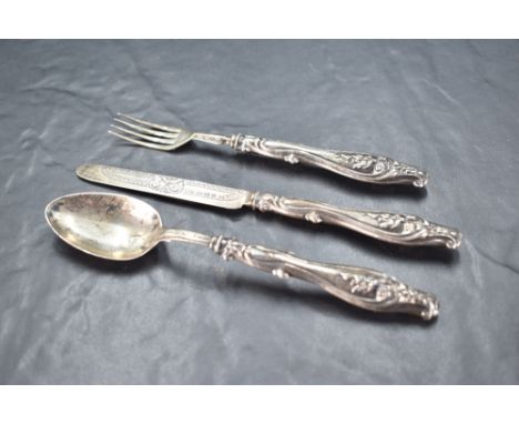 A Victorian silver christening set, comprising silver bladed knife, fork and spoon, the handles with embossed scrolling decor