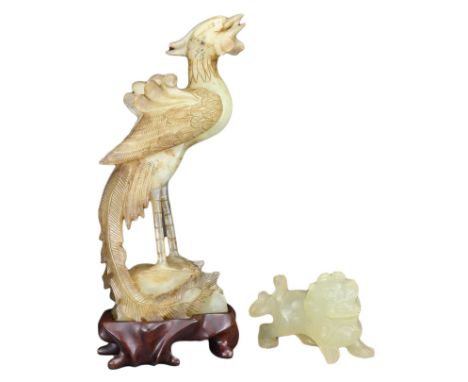 TWO CHINESE JADE CARVINGS. To include a carved jade model of a peacock on wooden display stand and a lion dog. Peacock 20.5cm