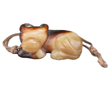 A CHINESE JADE WATER BUFFALO PENDANT. Carved with its legs tucked under its body, resting its head. In a light brownish-green