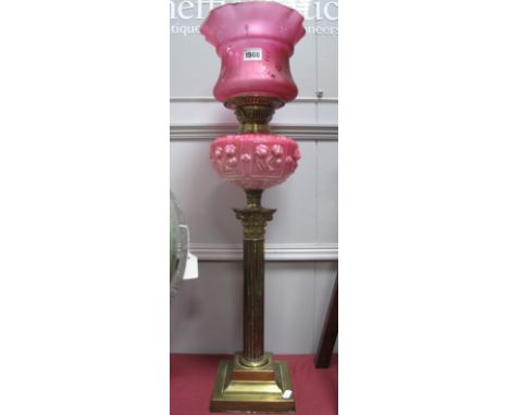 An Early XX Century Oil Lamp, with brass Corinthian column on stepped base, Cranberry glass well and shade.