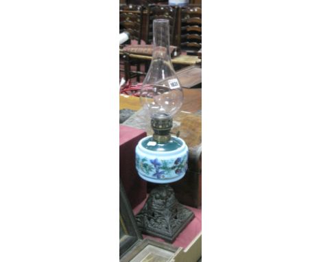 An Early XX Century Oil Lamp, with garden wall design to iron base, stamped reg No. 370396, painted turquoise glass well.