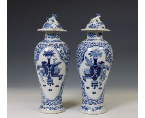 China, a pair of blue and white porcelain baluster vases and covers, 19th century, each painted with two cartouches of flower