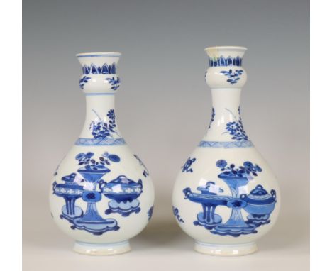 China, a pair of blue and white garlic-head vases, Kangxi period (1662-1722), each painted with antiquities, buddhist symbols