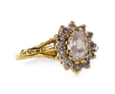 GEM SET CLUSTER RING, set with a central oval faceted white gem, surrounded by round white gems, on trifurcated shoulders, in