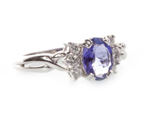 TANZANITE AND DIAMOND DRESS RING, set with a central oval faceted tanzanite flanked by two groups of diamonds, in eighteen ca