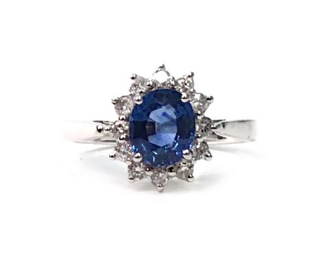 SAPPHIRE AND DIAMOND CLUSTER RING, set with a central oval faceted sapphire 6.9mm long and surrounded by diamonds, marked 750