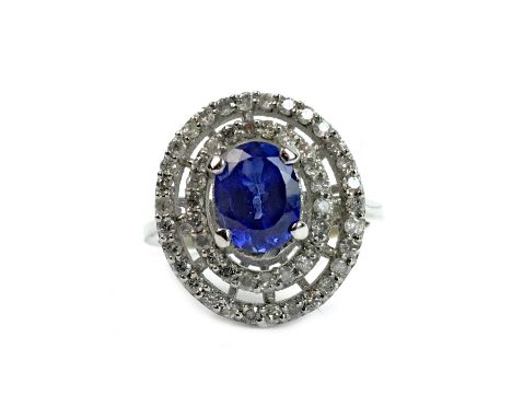 TANZANITE AND DIAMOND RING, set with a central oval faceted tanzanite 7.6mm long, within a double diamond halo, marked 14K, s