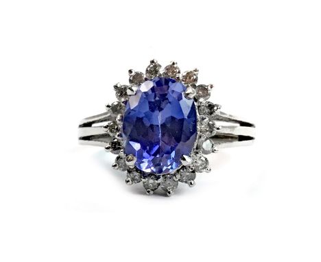 TANZANITE AND DIAMOND RING, set with a central oval faceted tanzanite 9.3mm long, surrounded by round brilliant cut diamonds,