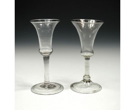 Two 18th century clear stemmed wines, both with slender bell bowls and folded feet, the marginally smaller with a bun knop ab