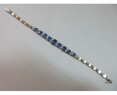 A mid 20th century sapphire bracelet, set with a line of graduated rectangular cushion cut light to mid blue sapphires separa