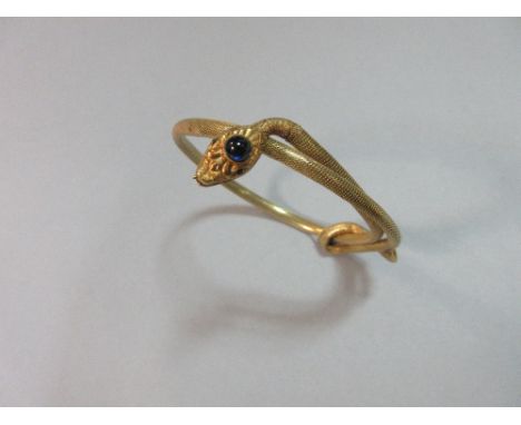 An adjustable 18ct gold and gem set snake bangle with Swiss import marks, the body of the snake formed from a tube of close s