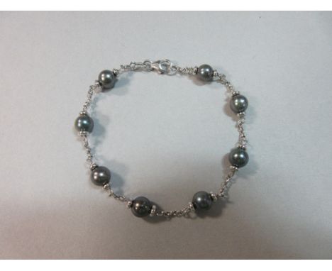 A black pearl and 18ct white gold bracelet, comprising eight 6-6.5mm black pearls sandwiched by white gold beads and joined b