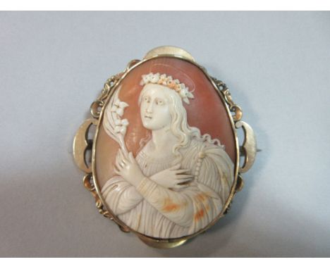 An antique shell cameo brooch, depicting an unidentified female saint, the young woman with long flowing hair, a crown of flo
