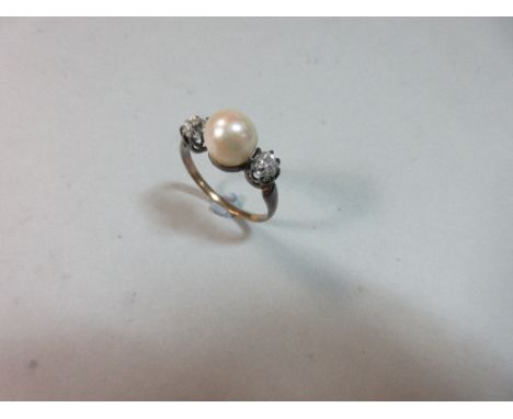 A three stone pearl and diamond ring, the 7.5mm pearl set between two old cushion-round cut diamonds, to a plain tapered shan