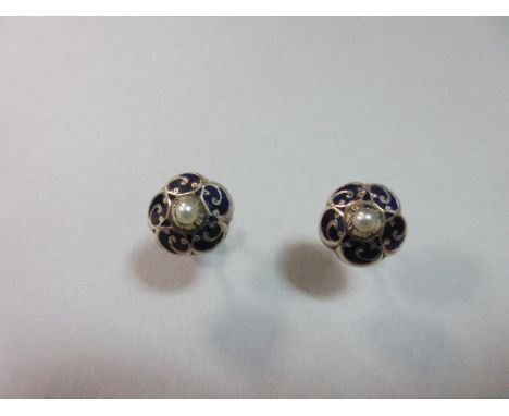 A pair of enamel and pearl flowerhead earstuds, each designed as a five-petalled boss with a scrolling pattern across the dar
