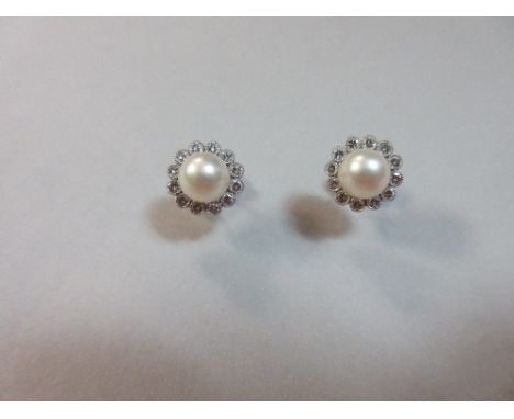 A pair of pearl and diamond earstuds set in 18ct white gold, each post headed by a 7mm pearl in a border of round brilliant c
