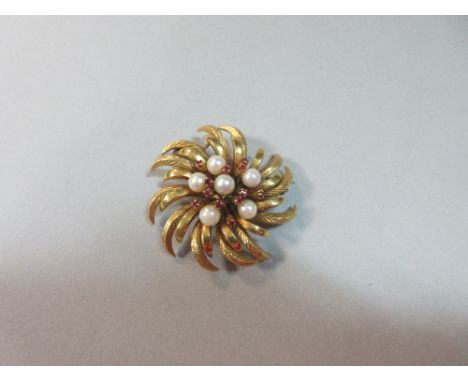 A flowerhead brooch set with pearls and rubies, the open cluster of six 5.5mm pearls randomly interspersed with twelve round 