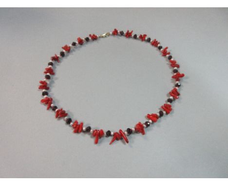 A coral, garnet and seed pearl necklace, with faceted garnet beads between seed pearls alternating with trios of red branch c