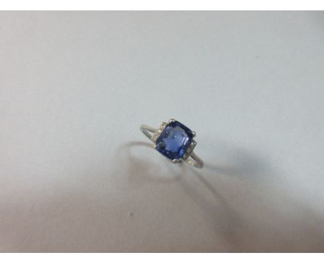 A lavendar blue sapphire and diamond ring, the rectangular mixed cut sapphire four claw set between bars each holding three r