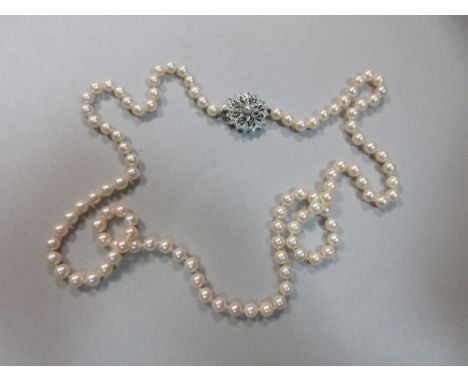 An opera length string of pearls with diamond and ruby clasp, the uniform 6mm cultured pearls individually knotted to a remov