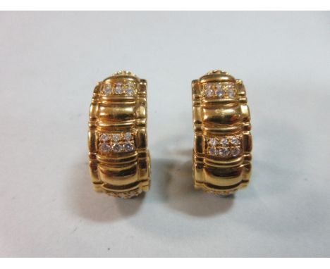 A pair of diamond set earrings by Piaget, each a looped and reeded band set at intervals down the length with sets of six rou
