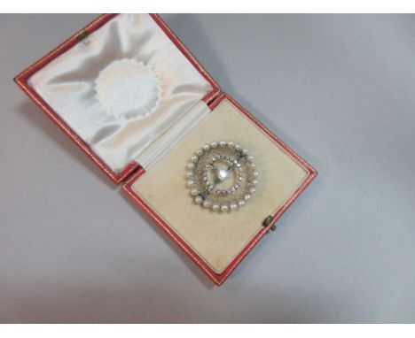 A diamond and pearl circular brooch, the circlet of 3.5mm pearls holding a fine geometric mesh of knife-edge bar work and inn
