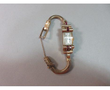 An odeonesque gold and ruby cocktail watch, the rectangular face with black Arabic numerals, Swiss movement with fifteen jewe