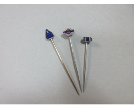 Three diamond and gem set stickpins, the first set with a sugarloaf cabochon amethyst and two baguette cut amethysts between 