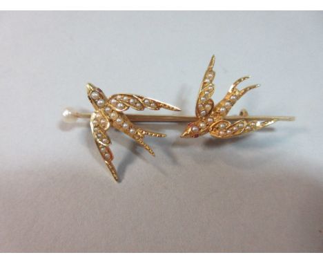 A twin swallow seed pearl set brooch, the two birds in swooping flight set with graduated seed pearls and ruby cabochon eyes 