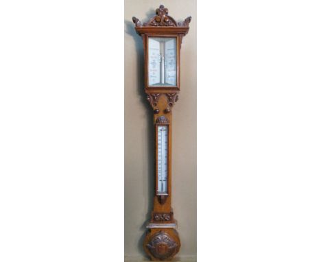 A Victorian carved oak stick barometer, the shaped pediment above twin registers, adjustable vernier knobs below, thermometer