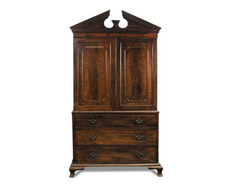 A George II style mahogany press, with break arch pediment and shelved interior, above three long drawers, leaf moulded cast 