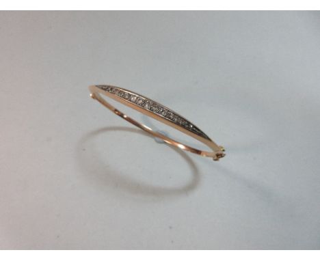A diamond set hinged bangle, of triangular cross-section and set to the front with a graduated line of old round cut diamonds