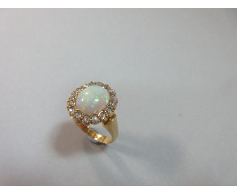 A late Victorian opal and diamond cluster ring set in 18ct gold, the oval opal cabochon in a border of rose cut diamonds to c