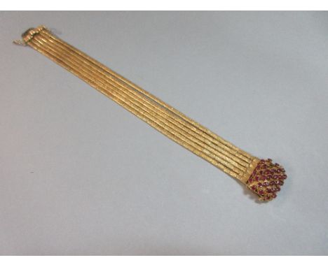 A multi-strand ribbon chain bracelet with ruby clasp, the six textured strands of close set links forming sinuous ribbons, to