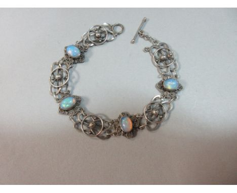 An Arts and Crafts opal set bracelet, with four oval cabochon opals collet set above diaper plaques with ropetwist decoration