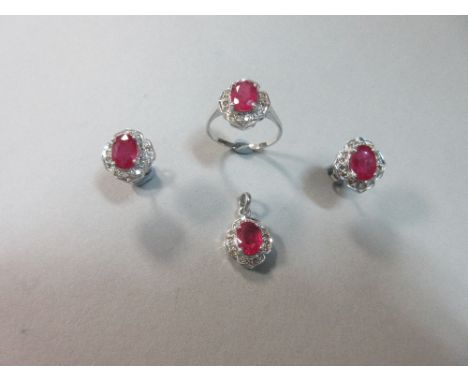 A treated ruby and diamond suite of ring, pendant and earstuds, each piece designed as an oval cut ruby within a quatrefoil s