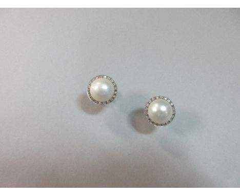 A pair of mabé pearl and diamond earstuds set in white gold, each mabé pearl collet set in a border of small round brilliant 