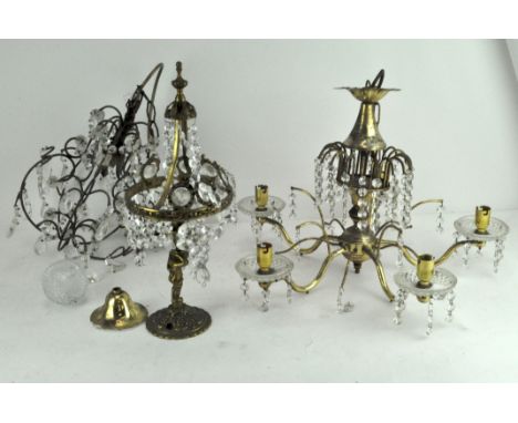 A gilt metal five light chandelier, a single light chandelier and a gilt metal lamp base with putti support, all with cut gla